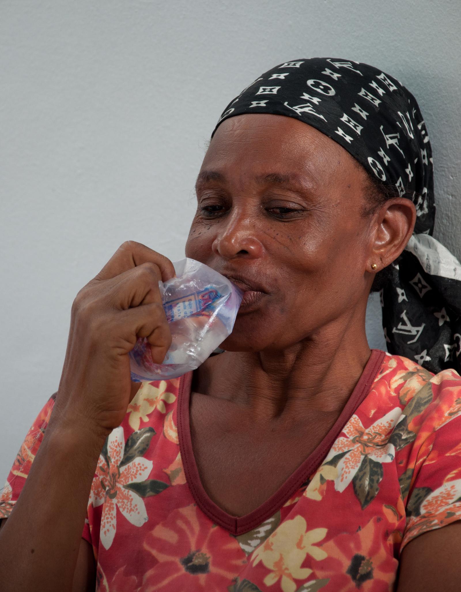Femme buvant de l'eau contenue dans un sachet plastique