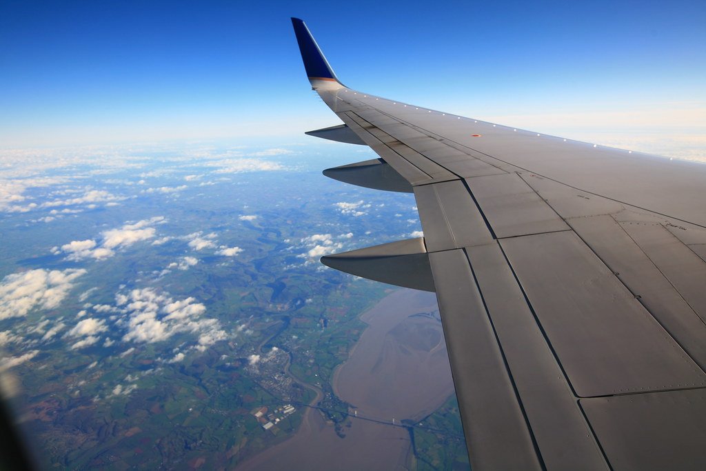 Vue depuis le hublot d'un avion survolant un paysage verdoyant