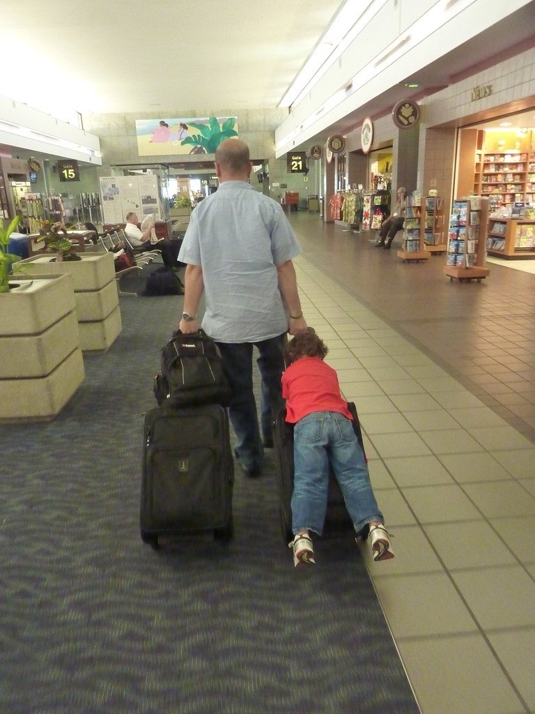 Père et enfant tirant une valise dans un couloir d'aéroport