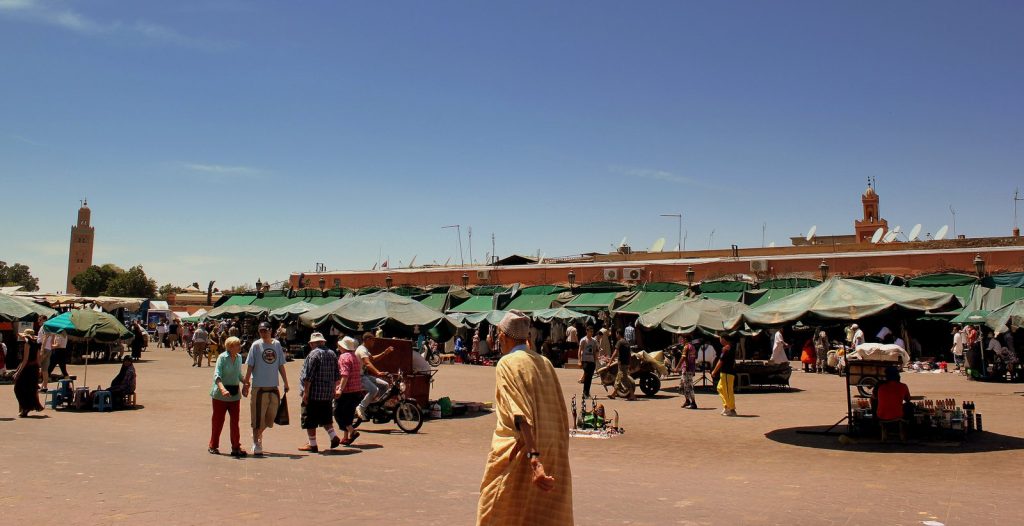 Place Jemaa el-Fna à Marrakech en pleine journée avec marchands et minaret de la Koutoubia